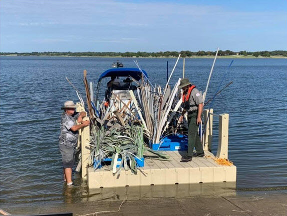 Photograph of US Army Corps of Engineers and volunteers loading structures on the tow barge, Proctor Reservoir, Texas, September 2019.