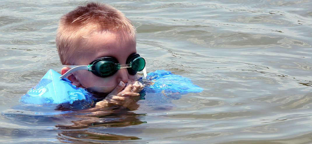 Boy in lake holding his nose