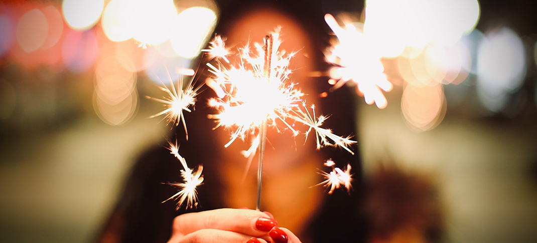 Woman holding a sparkler in front of her face