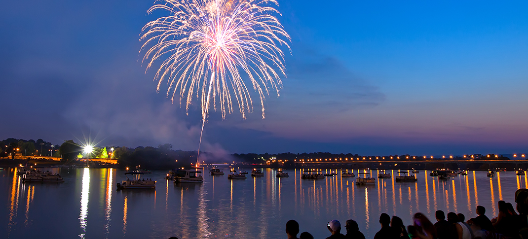 Fireworks over a body of water filled with boats