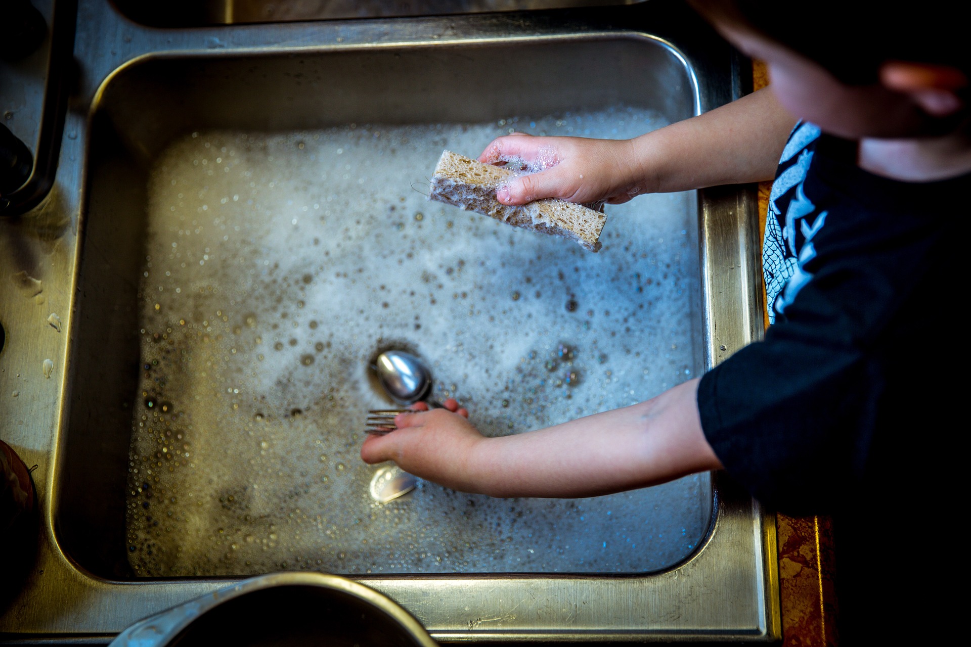 Child washing dishes in the sink