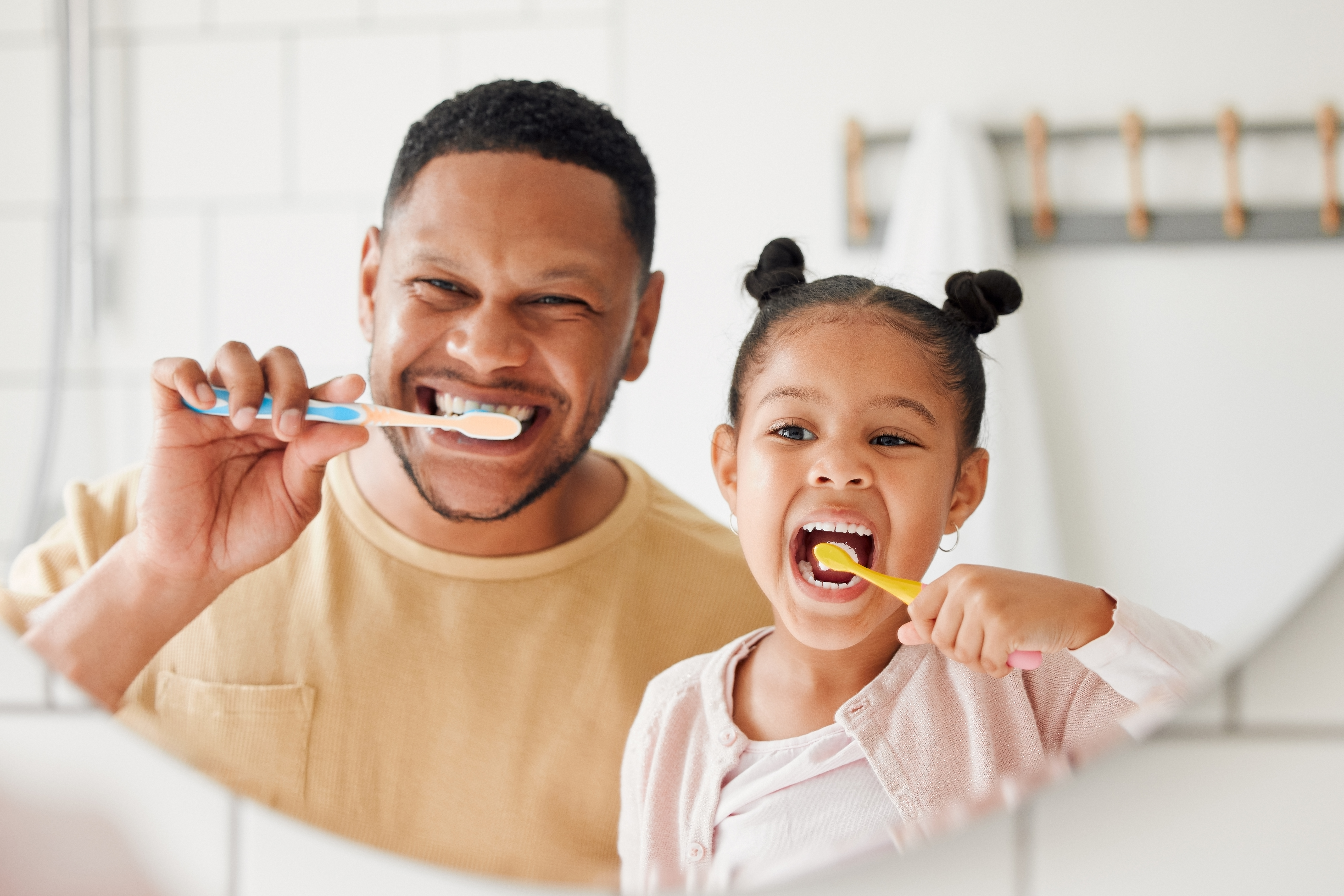 A man and child brushing their teeth in the mirror